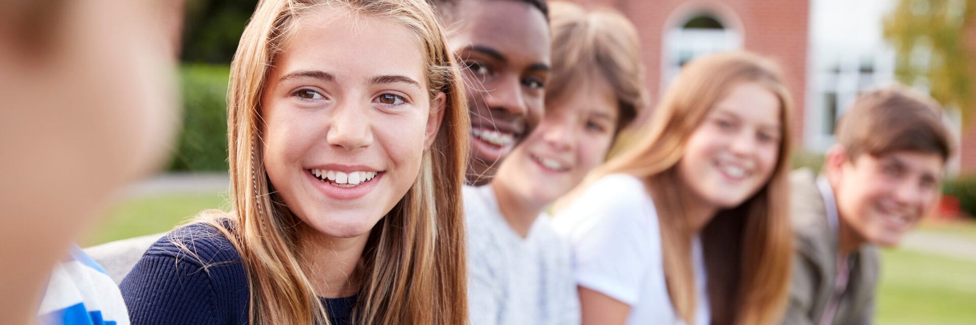 Group of teenagers in a row all looking towards you and smiling