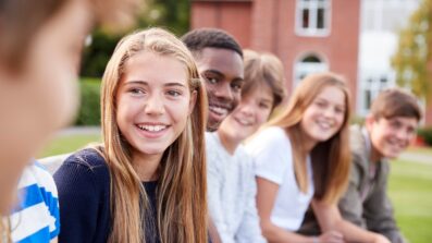 Group of teenagers in a row all looking towards you and smiling