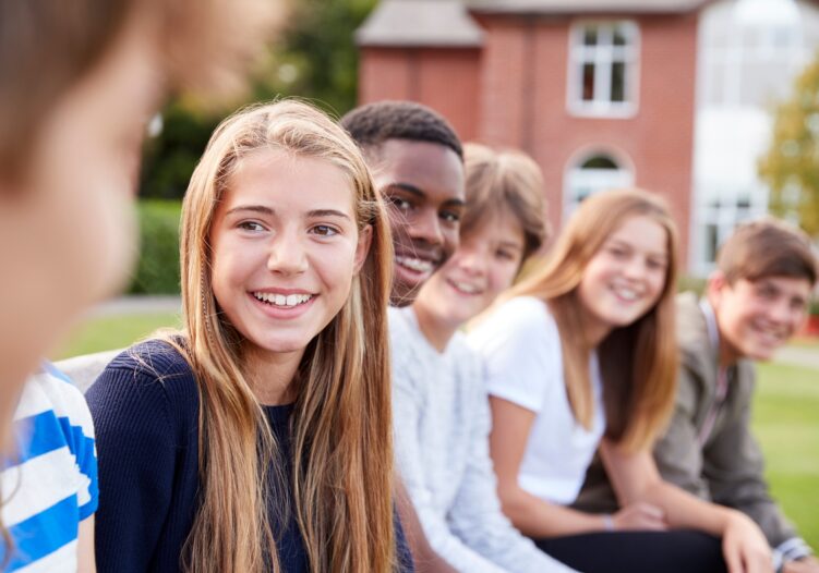 Group of teenagers in a row all looking towards you and smiling